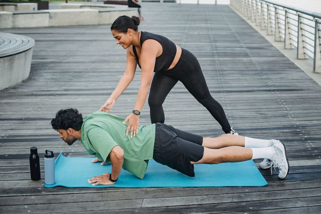 Personal trainer ajudando um aluno a fazer flexão